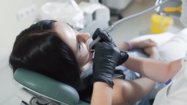 Paciente se encuentra en la silla dental durante el tratamiento dental con equipos modernos, cámara lenta — Vídeo de stock