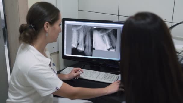 Dentista mostra ao paciente uma imagem de raio-x da mandíbula na tela, câmera lenta — Vídeo de Stock