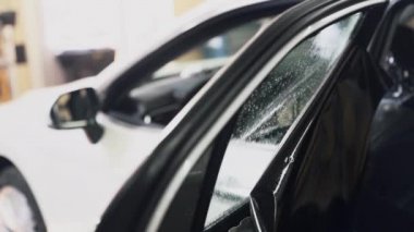 Yakın çekim işçisi araba camı, yavaş çekim için tint film yükler.