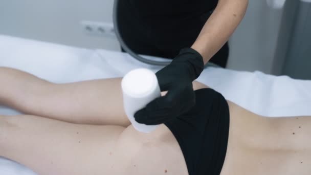 Закрыть, косметолог наносит специальный гель на женские ягодицы перед процедурой подъема — стоковое видео