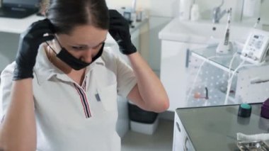 Diş hekimi hasta, yavaş hareket muayene önce tek kullanımlık kapak ve yüz maskesi koyar.