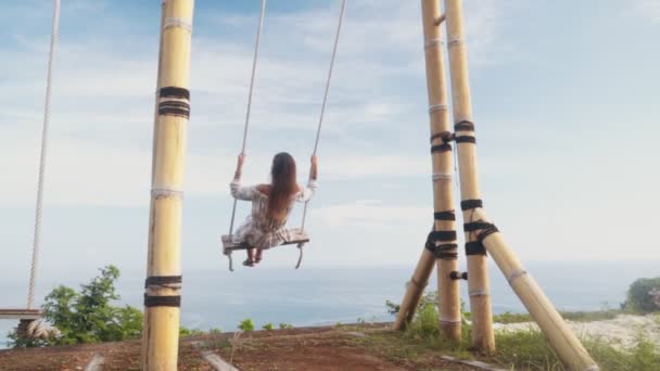 Slow motion, flicka gungor på swing, åtnjuter vacker utsikt över havet och vilar — Stockvideo