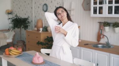 Bornozmutlu kız mutfakta sabah vakti sahiptir, çay içecekler, yavaş hareket