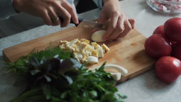 Закройте руки женщине с ножом, разрезающим варёное яйцо на деревянной доске. Концепция питания — стоковое видео