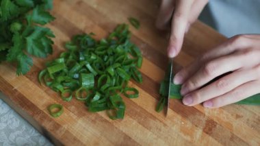 Kapatın tencerede ellerini tahta tahta üzerinde yeşil soğan kesme. Konsept sebze