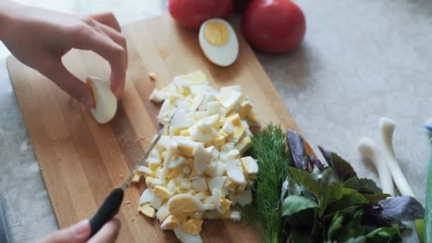 Cerrar cocine las manos con un cuchillo cortando el huevo hervido en una tabla de madera. Concepto alimenticio — Vídeos de Stock