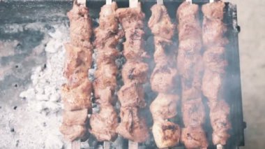 Yakın, açık havada ateş üzerinde şişler üzerinde et pişirme yukarıdan aşağıya görünümü, yavaş hareket