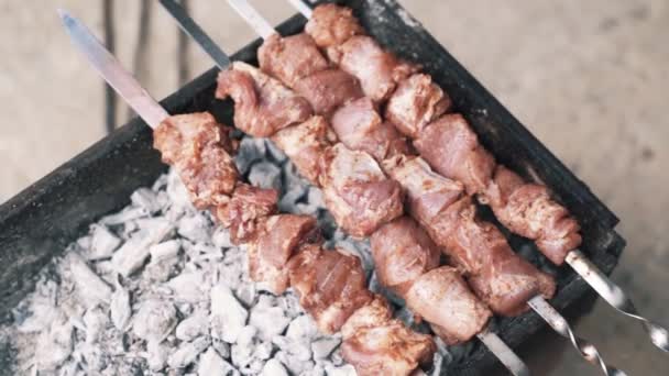 Zblízka si muži otáčejí pečené maso na špíze, pomalý pohyb, pouliční jídlo. — Stock video