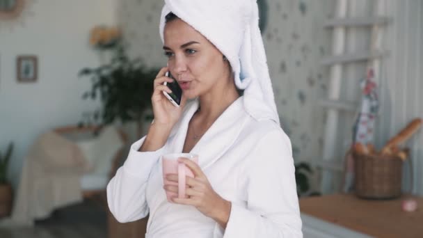 Ragazza con un asciugamano in testa, parla al telefono, tiene la tazza in mano, rallenta — Video Stock