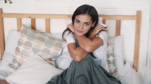 Πορτρέτο του χαριτωμένο κορίτσι κάθεται στο κρεβάτι στο σπίτι, κοιτάζει την κάμερα, χαμόγελα, αργή κίνηση — Αρχείο Βίντεο
