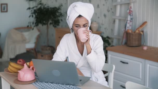 Fille avec serviette sur la tête ayant chat vidéo sur ordinateur portable et boissons thé, ralenti — Video