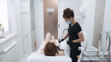 Güzellik uzmanı klinikte hasta vücudunda cilt sıkılaştırma işlemi yapar, yavaş hareket