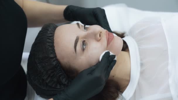 Close-up schoonheidsspecialiste reinigt huid van vrouw gezicht voor procedure, Slow Motion — Stockvideo