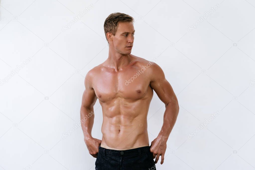 Portrait of sexy athletic man with naked torso poses on white background.