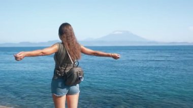 Sırt çantası ile Kız gezgin kollarını geniş yayılır, okyanus, dağlar manzarasına sahiptir