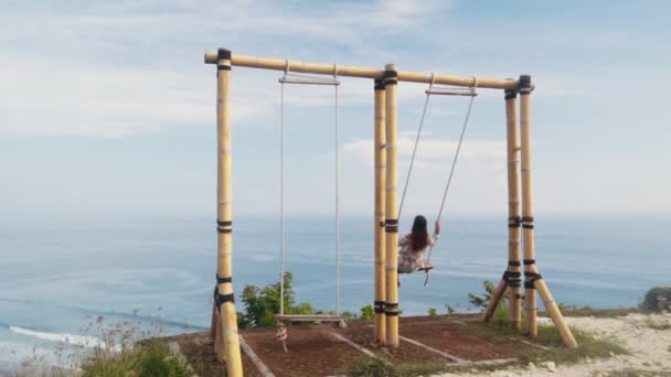 Reisende schwingt sich auf Schaukel über Klippe mit schönem Blick auf Meer, Zeitlupe — Stockvideo