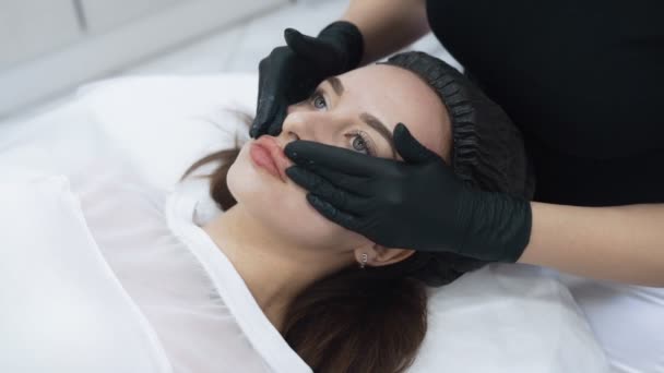 Primer plano cosmetólogo mano aplicar crema en la cara del paciente, masajearlo, cámara lenta — Vídeos de Stock