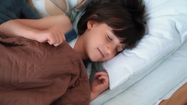 Маленькая девочка сладко спит в постели, просыпается и растягивается, замедленное движение — стоковое видео