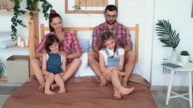 Ebeveynler iki kız için masaj yapmak, yatakta oturup, gülmek ve iyi vakit