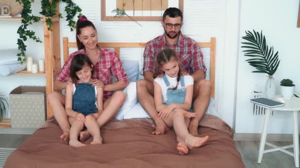 Os pais fazem massagem para duas filhas, sentam-se na cama, riem e divirtam-se. — Vídeo de Stock