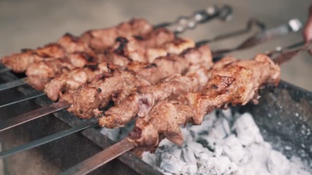 Zblízka si muži otáčejí pečené maso na špíze, pomalý pohyb, pouliční jídlo. — Stock video