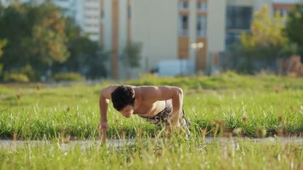 Отжимания спортсменов без рубашек на спортивных кольцах на атлетическом поле — стоковое видео