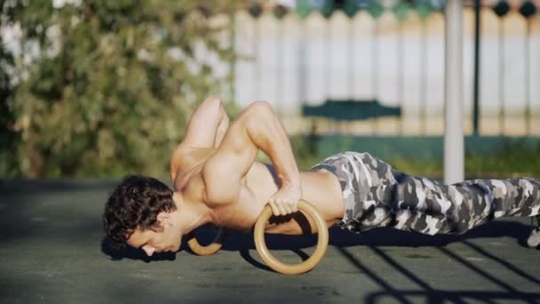 Primer plano atleta haciendo flexiones en los anillos deportivos en el estadio — Vídeos de Stock