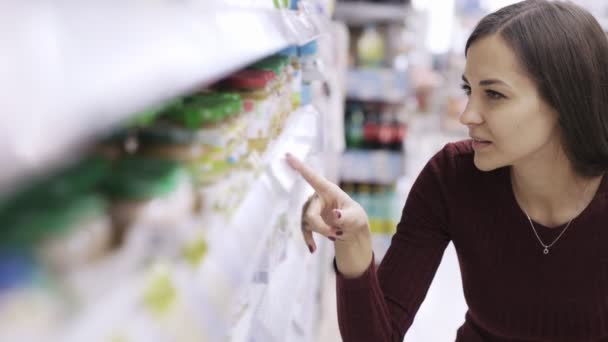 Portret kobiety patrzy na Tagi cenowe i szuka produktu na półce w supermarkecie — Wideo stockowe