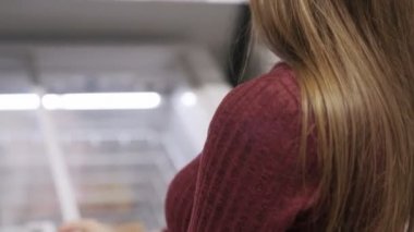 Kadının yan görünümü buzdolabı açar, süpermarkette dondurulmuş gıda arar