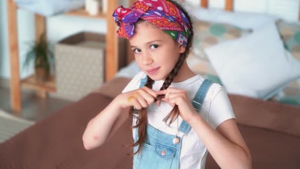 Retrato de linda chica lazos trenza con scrunchy y mira a la cámara, cámara lenta — Vídeos de Stock