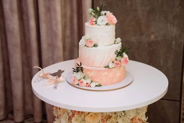 Big white wedding cake with pink roses on table