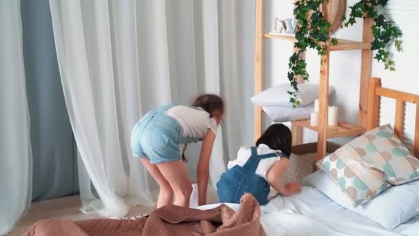 Due bambine fanno il letto, mettono cuscini, coprono con coperta, rallentano — Video Stock