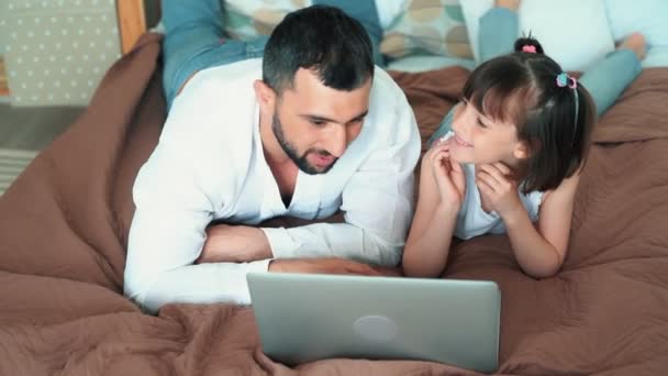 Papa en schattig kind gebruik laptop liggend op bed, speelt online spel, Slow Motion — Stockvideo