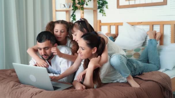 Счастливая семья, родители и две дочери смотрят мультики на ноутбуке, замедленная съемка — стоковое видео