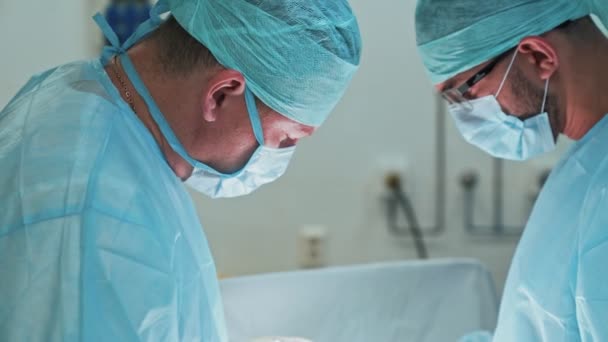 Equipe de médicos em roupas estéreis e máscara durante a cirurgia. Movimento lento — Vídeo de Stock