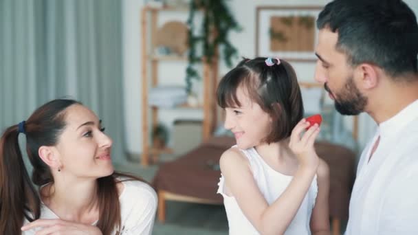 Счастливая семья на кухне, мама, папа и дочери едят клубнику, замедленной съемки — стоковое видео