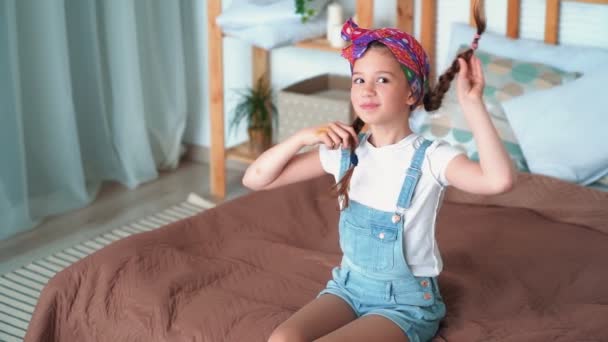 Retrato de chica feliz juega con trenzas largas, mira a la cámara, cámara lenta — Vídeos de Stock