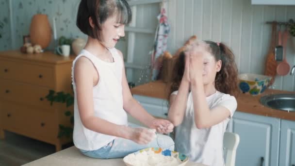 Cute sisters throwing flour at each other, have fun time at kitchen, slow motion — Stock Video