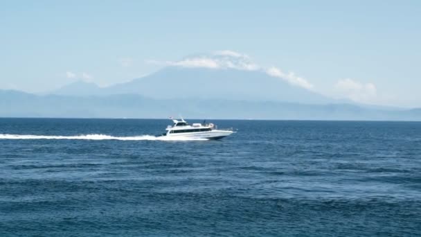 Яхта, плывущая по морю, стрельба с берега, горы на заднем плане, замедленное движение — стоковое видео