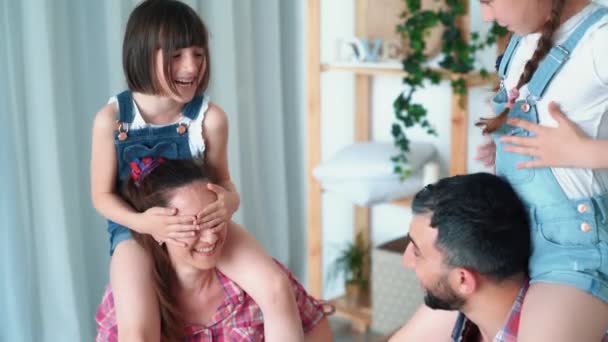 Döttrar sitter på axlarna av sina föräldrar och familjen har kul, slow motion — Stockvideo