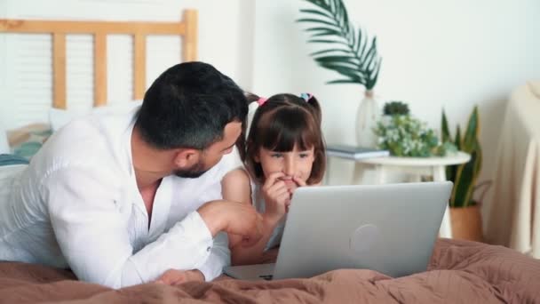 Padre joven con su hija aprende lecciones con el ordenador portátil, cámara lenta — Vídeo de stock