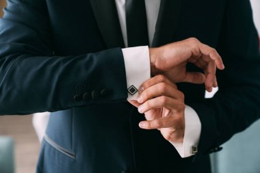 Yakın çekim damat eller kol düğmeleri koyar. Zarif beyefendi elbiseler, beyaz gömlek