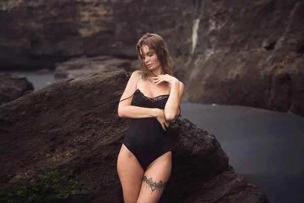 Tatilde siyah kumlu plajda bacak üzerinde dövme ile mayo seksi kız — Stok fotoğraf