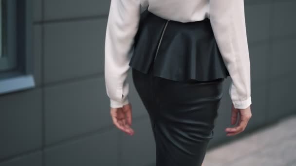 Backside view of woman butt in black leather skirt walking on street, slow motion — Stock Video