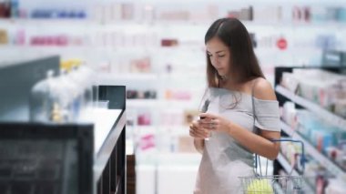 Pretty kız kozmetik mağazasında parfüm seçer, koklar, yavaş hareket