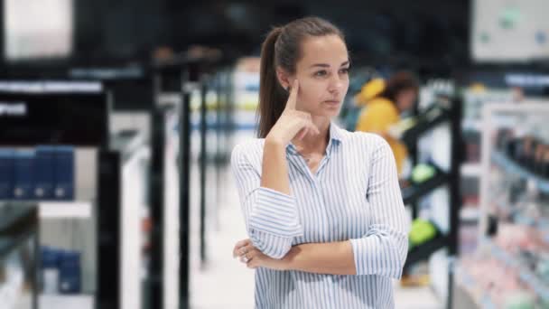 Retrato de chica en la tienda de cosméticos piensa qué producto comprar, cámara lenta — Vídeos de Stock