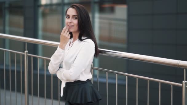 Beautiful happy girl in white blouse, black skirt posing on camera, slow motion — Stock Video