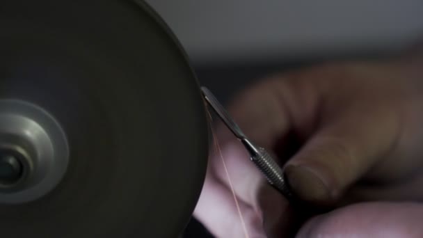 Close-up, trabalhador afia ferramentas de manicure em grindstone, faíscas em câmera lenta — Vídeo de Stock
