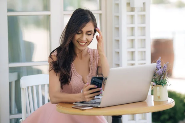 Schöne lächelnde Freiberuflerin nutzt Telefon und Laptop für die Arbeit im Café — Stockfoto