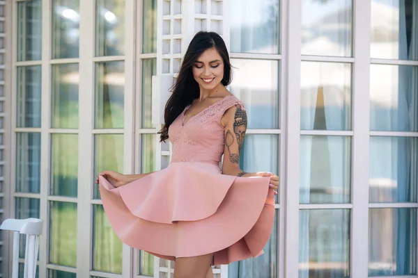 Lindo modelo con hermosa sonrisa en vestido rosa posando en la cafetería de la calle — Foto de Stock